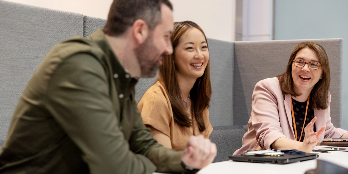 Trois employés assis dans un canapé discutant et souriant