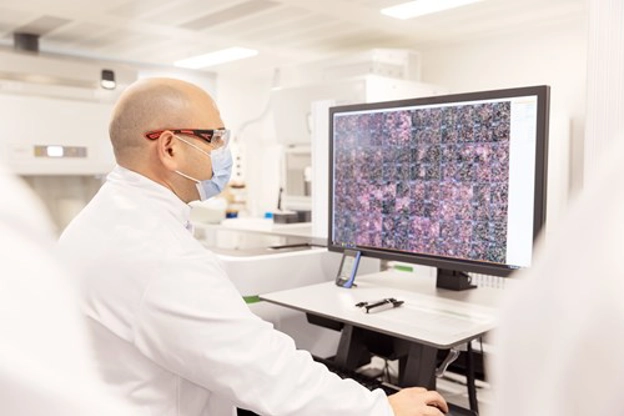 Homme avec un masque et des lunettes de protections devant un ordinateur