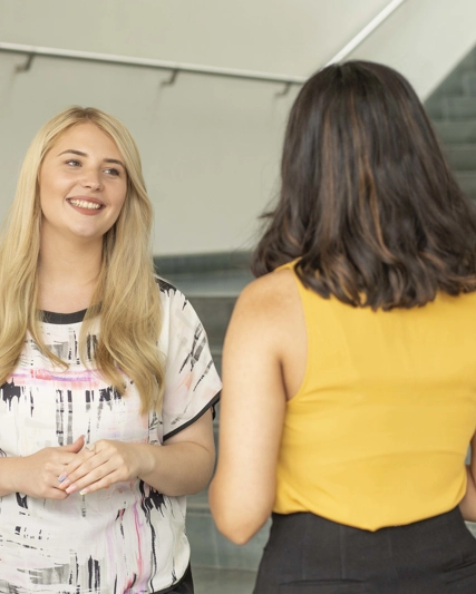 Deux employées discutant ensemble devant un escalier