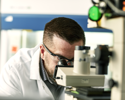 Scientifique regardant à travers un microscope dans un laboratoire