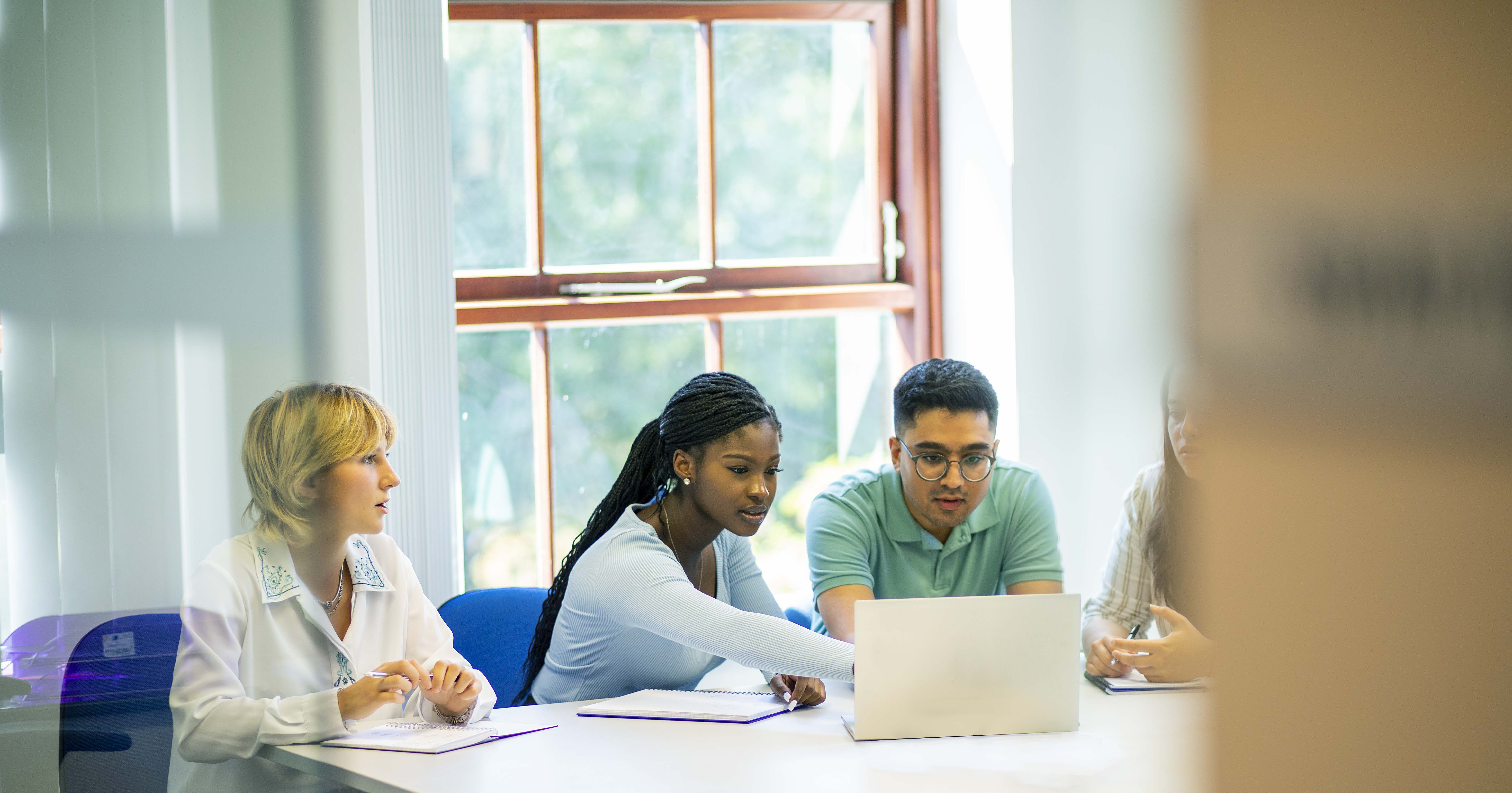 Quatre employés à une table travaillant ensemble sur leur ordinateur
