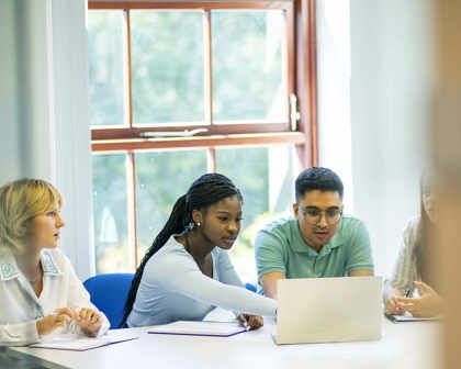 Quatre employés à une table travaillant ensemble sur leur ordinateur