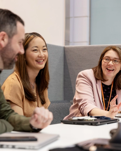 Trois employés assis dans un petit bureau discutant