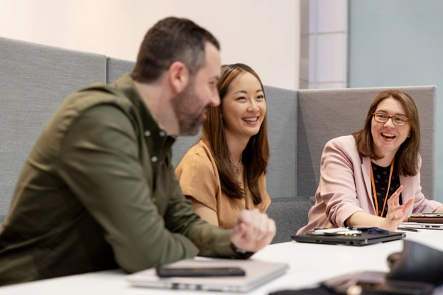Trois employés assis dans un petit bureau discutant